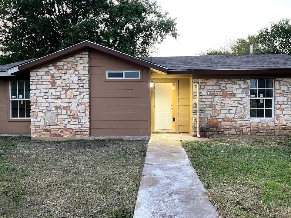 A renovated single-story Ayetex home with stone front, new siding and a lit porch
